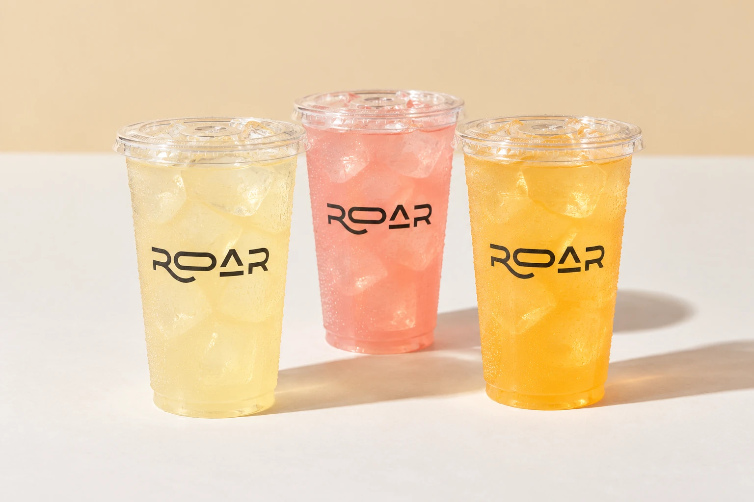 Trois limonades glacées ROAR, lisses et sans morceaux de fruits, sur le fond crème du studio
